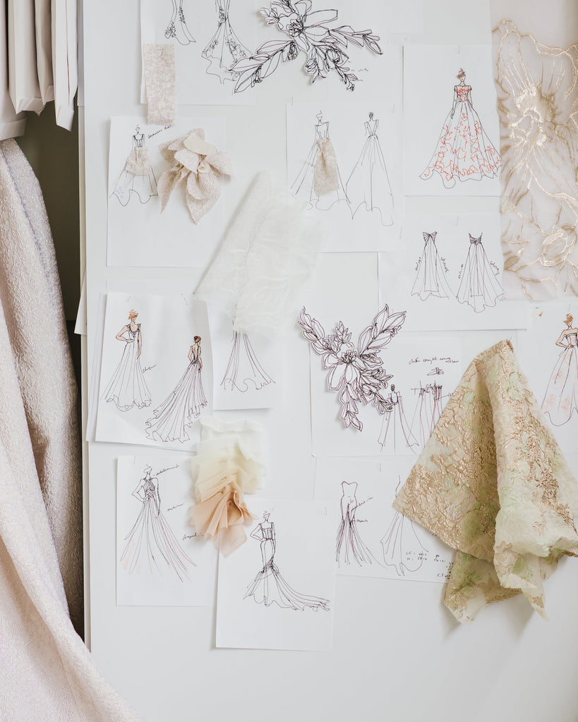Design sketches and fabric samples on a white board with clothing items around.